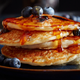 A stack of blueberry pancakes drenched in syrup... or are they???